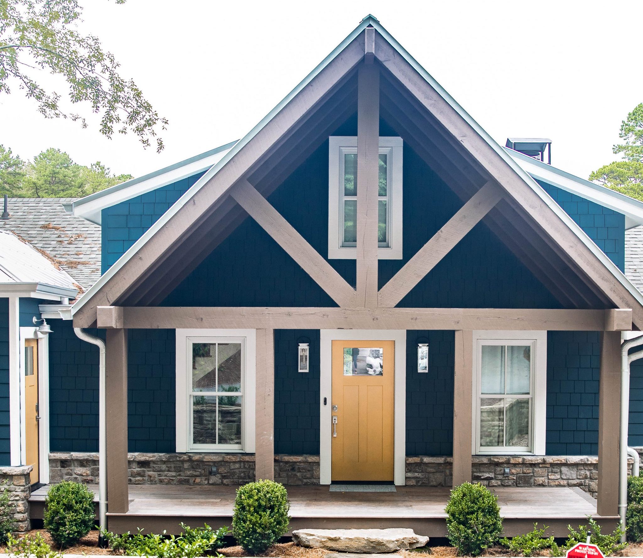 lakehouse exterior blue and white and yellow with raw wood exposed beams