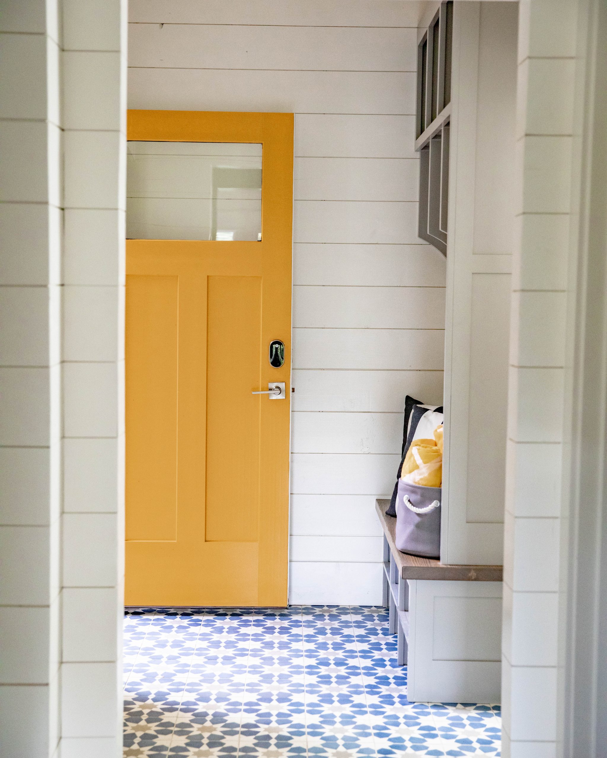 This is the yellow front door of the Lake Burton Lakehouse Remodel. It leads to a mudroom with a beautiful blue and white floor.