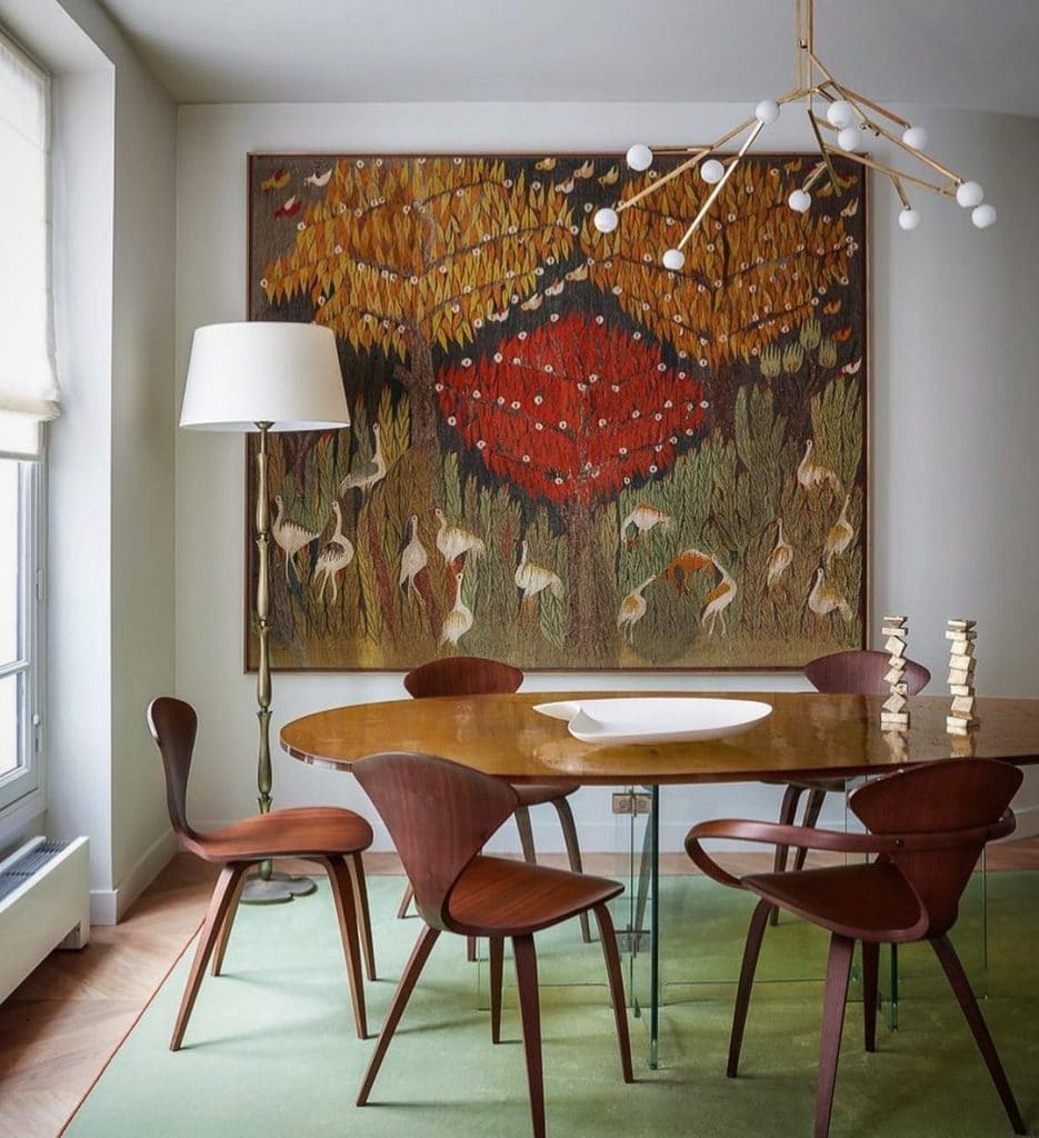A mid century modern example, featuring a quintessential round dining table with iconic chairs and a large bird artwork behind
