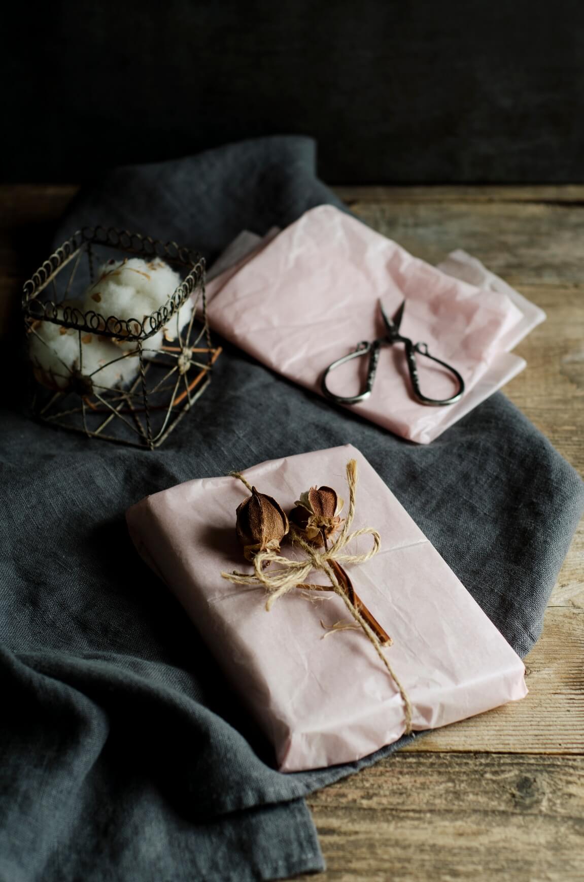 Gifts bought and wrapped with intention, wrapped with a natural paper and dried flower bouquet; caught just after finishing up, the image suggests intention in the holiday season
